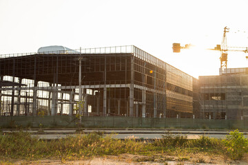 Obraz premium Silhouette of industry warehouse factory building framework with metal structure in construction site against sunset sky background, low angle view with copy space