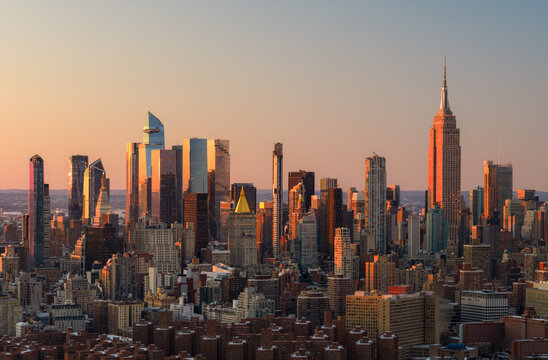 Aerial view of skyscrapers catching the warm glow of the setting sun, including the Empire State Building, New York, New York, United States.
