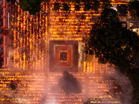 Aerial view of countless flickering candles casting a warm glow across the ceremonial grounds, illuminating a central structure with intricate designs, Baradi, Dhaka, Bangladesh.