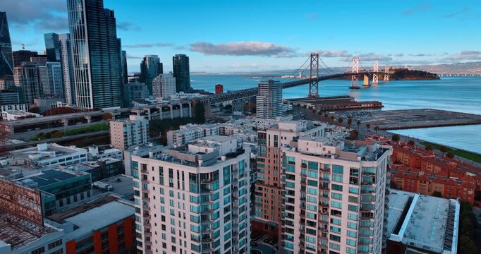 Flying over the rooftops of the high buildings in San Francisco, California, USA. View on the Oakland Bay Bridge with hectic traffic.
