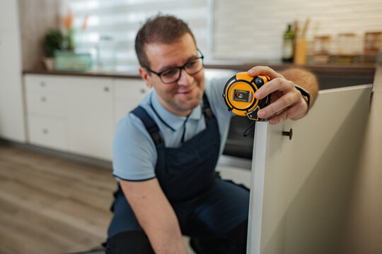 Handyman measuring kitchen cabinet for home renovation
