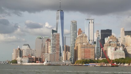 Obraz premium New York City Manhattan Downtown skyline from ferry boat to Liberty Island, United States. Financial District cityscape, World Trade Center skyscraper tower. Urban buildings architecture. Rain clouds.