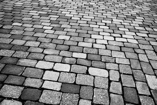 Monochrome cobblestone pavement stone pattern and texture on urban street surface creating timeless background for design and travel themes
