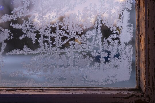 Window with old window frame and frosty ice crystals in the evening light, Finland