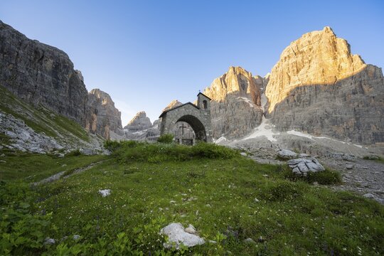 Cappella Ai Brentei chapel Memorial for injured mountaineers at the Rifugio Ai Brentei mountain hut, rocky peaks at sunrise with alpine glow, picturesque mountain landscape, Brenta, Trentino, Italy