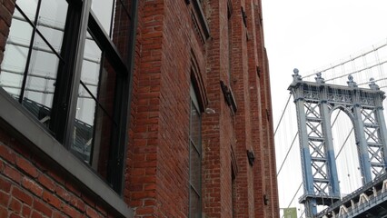 Fototapeta premium Manhattan bridge in Brooklyn Dumbo, New York City, United States of America. Red brick building architecture, reflection in windows on Washington street. Tourist landmark in NYC, USA.