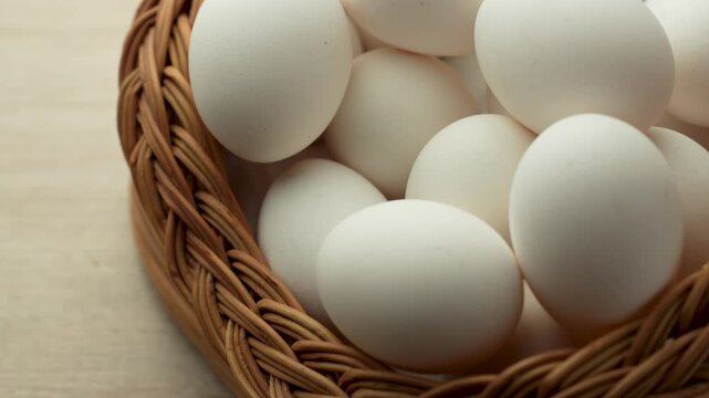 Hand Taking Fresh White Egg from Wicker Basket. Close-up of a hand reaching into a traditional woven wicker basket to select a fresh white chicken egg, representing healthy choices and organic farming