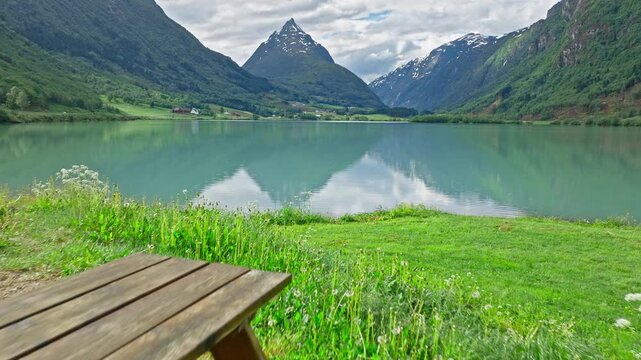 Eggjenibba and Bergheimsvatnet lake reflection in Norway. Turquoise water mirrors mountains and clouds on a calm summer day, creating a serene alpine mood.