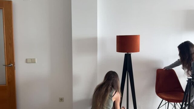 Influencer y amiga preparando el set con silla y l&aacute;mpara decorativa
