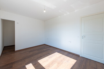 Fototapeta premium Minimalist Empty Room with Wooden Flooring and White Walls in Bright Lighting