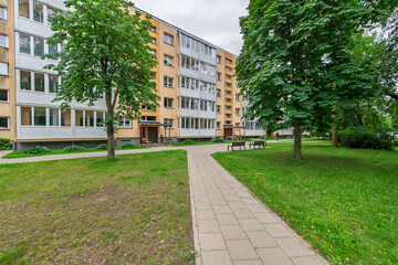 Obraz premium Residential Apartment Building With Park Benches and Green Surroundings Outdoors
