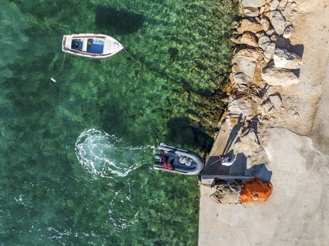 Rubber dinghy moors at the quay wall, aerial view, turquoise water, Greece
