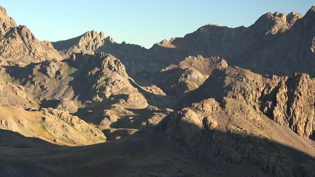 Time lapse of sunrise over treeless arid mountains in Pakistan showing dramatic light change. Warm dawn colors reveal rugged desert ridges and harsh highland terrain.