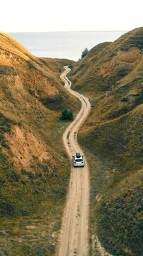 Beautiful nature landscape and white tourist car traveling to the sea in a deep canyon. Amazing place to travel. View from the drone on the car. A drone watching a car.