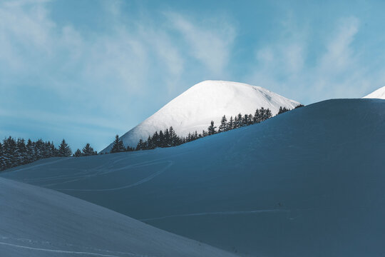 snow covered mountain near col de lautaret in french alps with illuminated height and pine forest