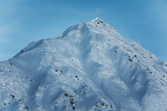snow covered mountain near col de lautaret in french alps, in blue atmosphere and clear sky