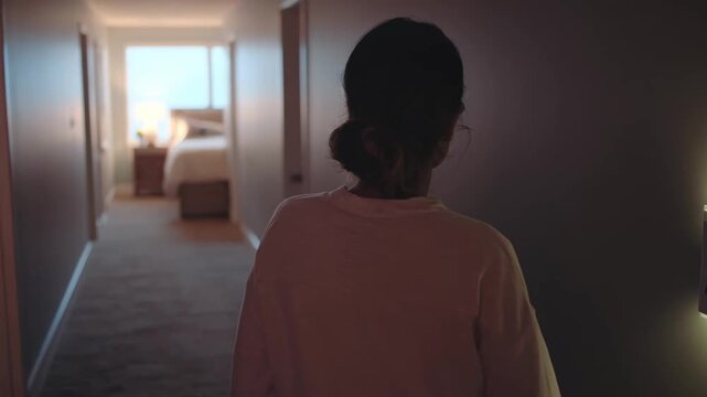 Medium shot of an individual adjusting a motion sensor night light in a hallway focusing on lighting enhancements to avoid nighttime slips.