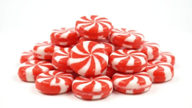 Red and white swirl hard candies piled on a clean white background sweet treat confectionery concept