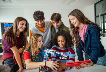 Group of high school students building robotic arm in STEM classroom.