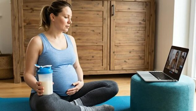 Healthy Pregnancy Journey: Expectant Mother Engages in Online Prenatal Fitness Class with Protein Shake at Home