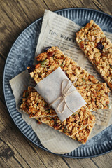 Gluten-free oat granola bars with nuts and berries on round vintage metal tray