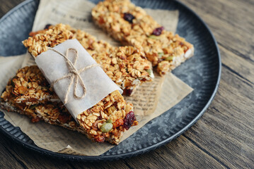Gluten-free oat granola bars with nuts and berries on round vintage metal tray