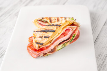 Folded tortilla wrap with cheese bacon ham and tomatoes on clean background
