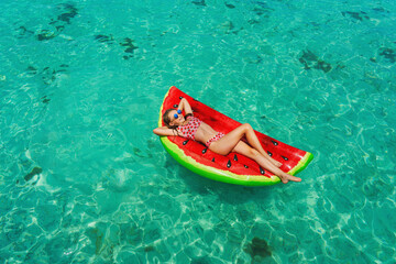 Floating mattress and happy child in the ocean with perfect blue water. Relaxation, vacation concept with copy space. Colorful vacation concept.