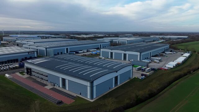 Biggleswade, United Kingdom - 24 January 2026: Aerial view of distribution warehouses and parked trucks, contrasting the industrial zone with the adjacent green fields.
