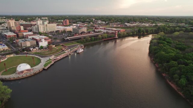Aerial drone landscape view of downtown Montgomery, Alabama riverfront water park along gun island shoot river with baseball ballpark stadium, green lawn, buildings, high-rises, and capital city roads
