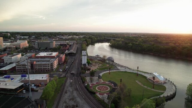 Aerial drone landscape view of downtown Montgomery, Alabama riverfront water park along gun island shoot river with baseball ballpark stadium, green lawn, buildings, high-rises, and capital city roads