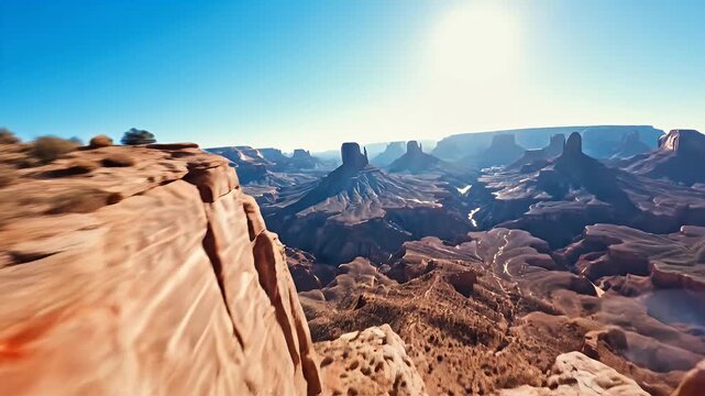 An aerial view showcases a sun-drenched canyon with layered rock formations and distant mesas