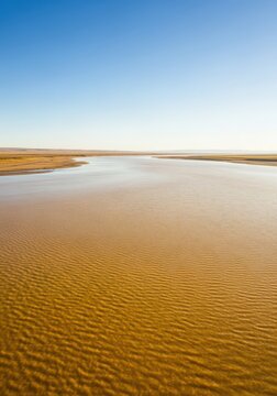 Vast landscape featuring a wide, powerful, slow-moving river colored a distinctive yellow-brown due to heavy sediment and loess deposits, remote, wide, scenic