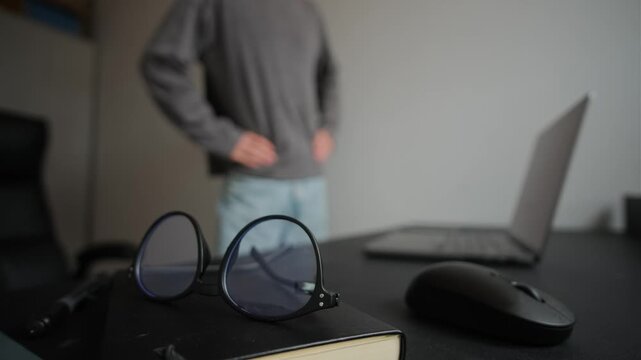 Healthy work break concept, office desk in focus with blurred man doing stretching exercises