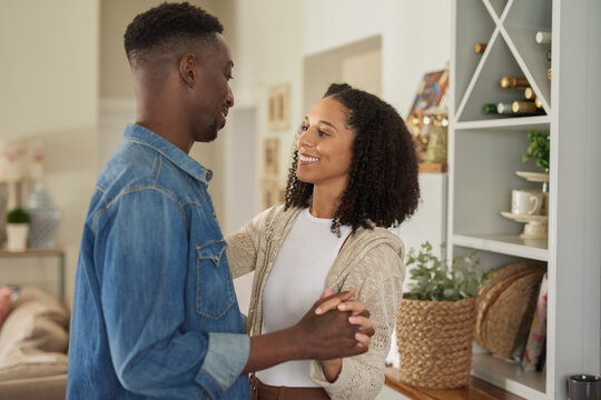Loving young multiracial couple dancing hand in hand together at home