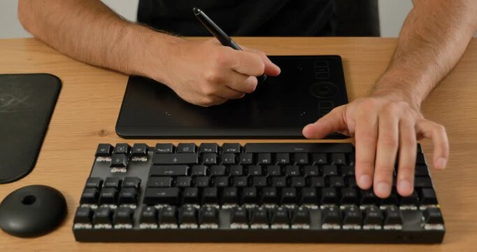 Creative professional using keyboard and graphic tablet at desk.