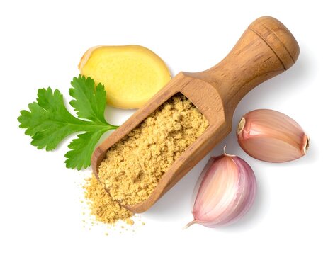 Ginger powder in a wooden scoop with garlic clove on white background