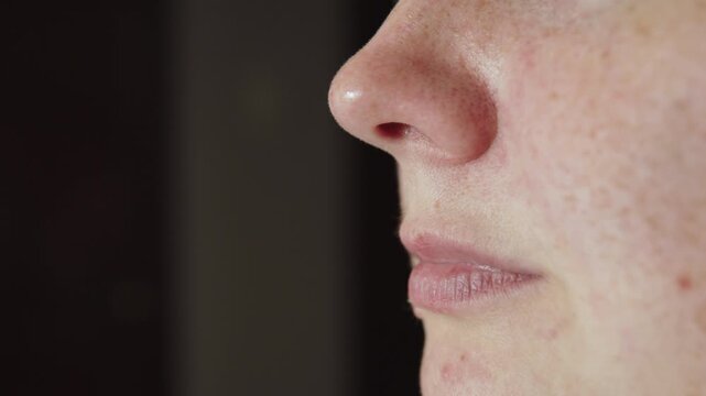 Calm deep breathing through nose by woman, close-up side shot. Female figure breathing noisily due to nasal congestion during vasomotor rhinitis and dry air.