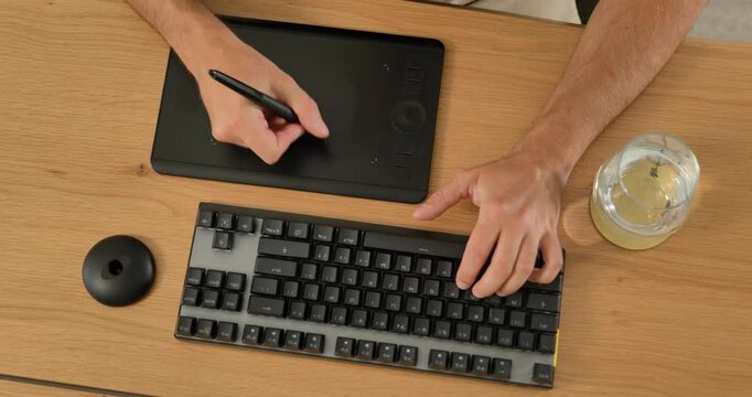 Creative professional using keyboard and graphic tablet at desk.