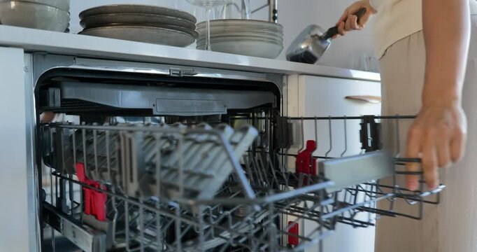 Woman loading dishes into dishwasher in modern kitchen
