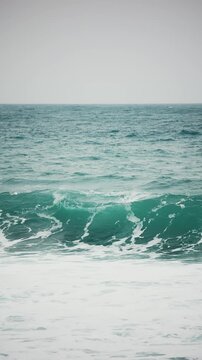 Vertical video of perfect Ocean wave rolls and breaks in storm