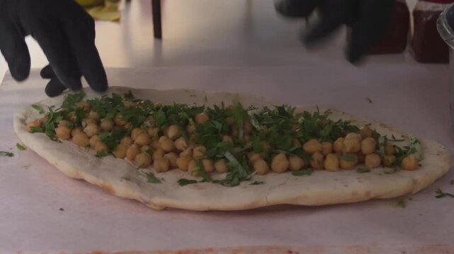 Chef adding fresh parsley and onions to a traditional Turkish chickpea wrap (Nohut Durum)