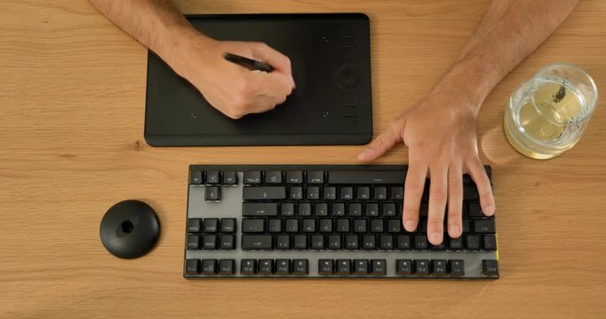 Creative professional using keyboard and graphic tablet at desk.