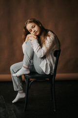 Studio portrait of a girl in a pensive mood, sitting on a chair