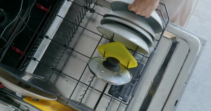Woman loading dishes into dishwasher in modern kitchen