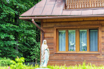 Traditional wooden house with Mary statue in Poland