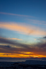 Fototapeta premium Panorama of Athens at sunset with a view of the Acropolis. The city lit up at night against the backdrop of enchanting clouds and a mesmerizing sunset. A peaceful picture of relaxation 