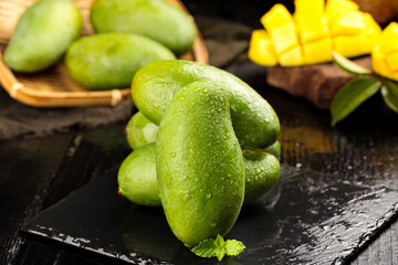 Fresh Green Mangoes from Vietnam - Tropical Fruit Variety Gathered Together on Rustic Wooden Surface © TranThi