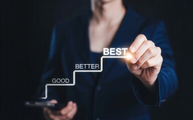 Obraz premium Business person drawing a staircase of improvement with words good, better, best on a dark background