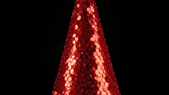 A close-up view of a cone-shaped structure composed of red, textured, overlapping scales. Black background